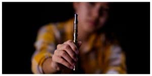 Teenage girl vaporize cannabis through a vaporizer containing cannabis oil in a tube after electrical heating