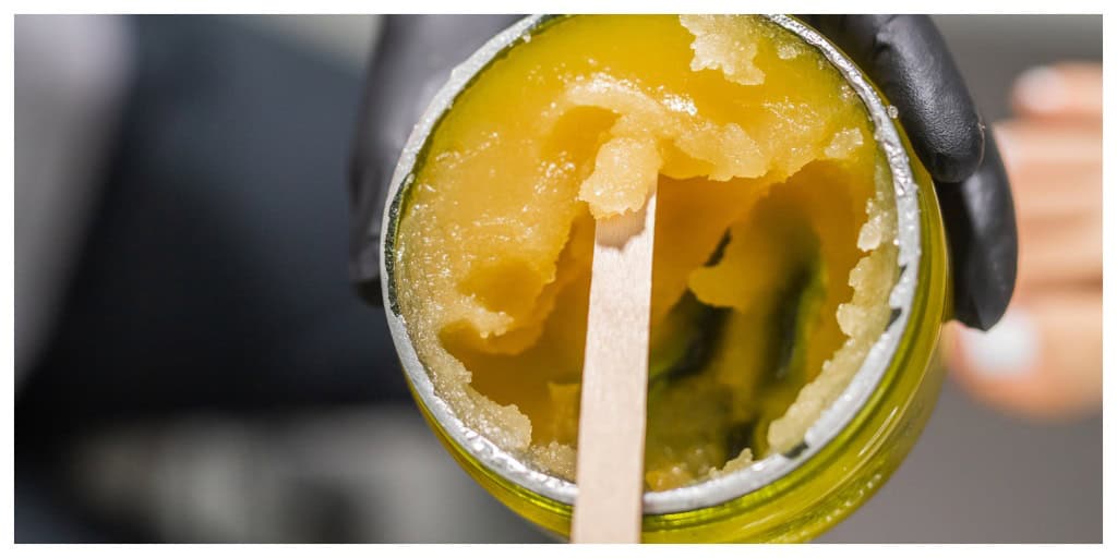 THC resin in glass jar in female hand.