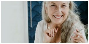 older woman smiling whilst holding a joint