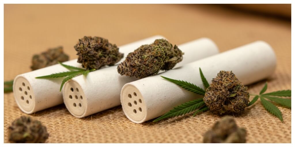 girl preparing a joint using activated carbon filters for smoking on a surface with cannabis buds